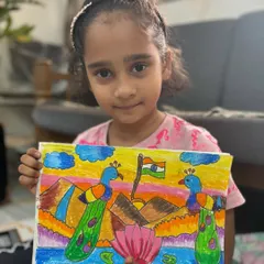 A young artist holds her vibrant Republic Day drawing featuring peacocks and the Indian flag. Our festival-themed classes are a creative way to celebrate national pride.