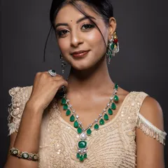 A model adorned with a complete emerald and diamond bridal jewellery set, including a necklace, earrings, and bangles. This is a perfect shot for a luxury bridal jewellery catalogue.