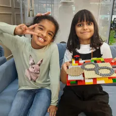 Best friends and building buddies! Two girls proudly show off their colorful LEGO creation at our workshop. These sessions are great for fostering collaboration and social skills.
