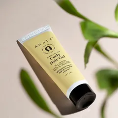 A lifestyle product shot for Arata's Curly Hair Gel, using natural light and foliage to evoke the product's natural ingredients. This style helps customers visualize the product in their own daily routine.