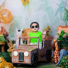 The king of the jungle has arrived. This baby is looking cool in his sunglasses, waving from his safari jeep, surrounded by plush jungle animals.