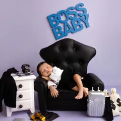 Here's the real boss. This adorable "Boss Baby" themed newborn shoot features a tiny baby sleeping soundly in a miniature leather armchair, surrounded by fun props like a briefcase and money bags.