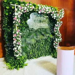 This greenery wall photo booth is framed with an arch of pink and white flowers. A custom "Better Together" neon sign adds a modern and personal touch, perfect for a wedding anniversary or engagement party.