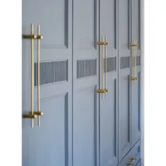 A close-up of the custom brass handles on a grey wardrobe. The design includes a small fluted detail, adding a subtle texture that elevates the entire piece.