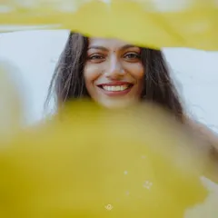 A beautiful, happy portrait of a bride during her Haldi, her face framed by a flowing yellow dupatta.