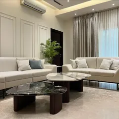 A wider angle of the Sobha International City living room, showing the clean lines of the furniture and the subtle elegance of the wall paneling. Every element is chosen to contribute to a feeling of understated luxury.