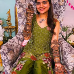 A smiling bride-to-be posing with her intricate, full-coverage bridal mehandi.