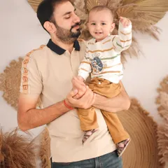 A proud father holds his son, who points up with excitement. This candid interaction during a family studio session captures a moment of discovery and connection.