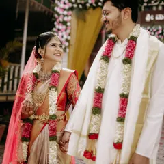 A candid moment of shared smiles between the bride and groom, adorned in traditional garlands, as they walk together, beginning their new life.