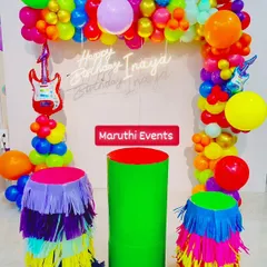 A vibrant rock-and-roll fiesta theme for Inaya's birthday. This colorful setup has a neon sign, guitar foil balloons, and plinths with multi-colored tassels.