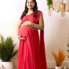 A full-length portrait showcasing a beautiful red maternity gown against a bright, boho-inspired setup. This style is perfect for a modern and chic look.