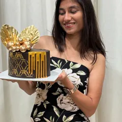 A photo of me with a birthday cake I made. This one is a rich chocolate cake with a modern geometric stencil design and golden drip.