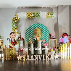 A fun jungle safari theme for a second birthday, with monkey, lion, and elephant characters and a green and gold balloon arch.