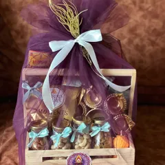 A beautiful wooden crate Diwali hamper filled with dry fruits, chocolates, and traditional diyas, all wrapped in elegant purple tulle with a white satin bow.