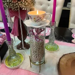 A detail from the coquette tablescape, showing how I use other elements to support the centerpiece. A teacup candle holder and vibrant magenta tapers complement the floral arrangement and enhance the whimsical, romantic mood.