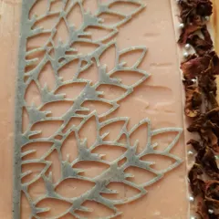 A detailed look at the custom Charcoal Rose soap. You can see the delicate stencil work, the line of dried rose petals, and the two-tone layers of pink clay and charcoal.
