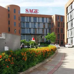 A view of the Sage University campus in Indore, with its distinctive curved terracotta-clad walls and landscaped entry. The design is carefully integrated with the natural terrain to create a serene learning environment.