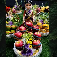 This doll, dressed in a purple silk pavadai, is the centerpiece of a fruit platter arrangement. I use decorated apples and oranges to create a colorful and auspicious display for any celebration.