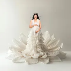 A fantasy portrait of a mom-to-be "blooming" from within a giant white flower prop. This creative concept beautifully symbolizes the new life she is bringing into the world.