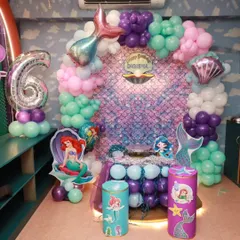 I believe in making dreams come true with magical themed parties. This stunning mermaid birthday setup, complete with an iridescent backdrop and under-the-sea balloon decor, shows how I transform my space into a fairy tale world for your child's special day.