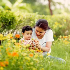 A mother and child exploring flowers in a sunlit garden. The golden hour light adds a warm and dreamy quality to our outdoor photos.