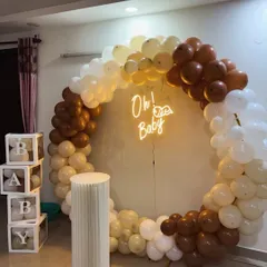 Our 'Teddy Bear Hug' theme is a crowd favorite for its cozy and neutral charm. This baby shower setup features a full ring balloon arch in brown, beige, and white, an 'Oh! Baby' neon sign, a classic cake plinth, and our popular transparent 'BABY' boxes.