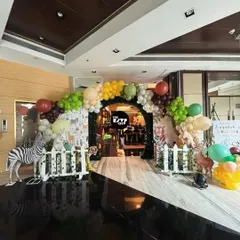 A different take on a jungle entrance, this one features a balloon arch and a path lined with a white picket fence and life-like animal props.