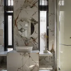 A marble sanctuary where veins of Indian marble flow seamlessly across surfaces. Tall windows reflect natural light, and a circular mirror amplifies the sense of space and openness.