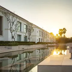 The hotel's guest wings overlook a reflective water body at sunset, a design choice that enhances the sense of calm and connection to nature.