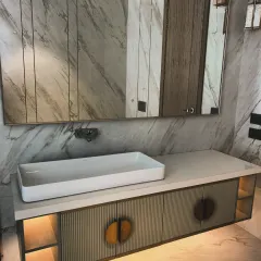 A close-up of a floating bathroom vanity featuring intricate CNC-cut patterns on the cabinet doors with a premium PU finish. This piece combines artistic texture with practical, moisture-resistant materials, complete with under-cabinet lighting for a hotel-like ambiance.