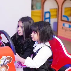 Two girls take the wheel together in one of our car racing arcade games.