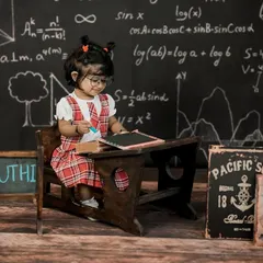 Back to school! This adorable little student is ready to learn at her vintage desk, with a chalkboard full of equations in the background.