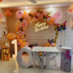 For this first birthday, I designed a magical butterfly theme. The setup includes a custom 'ONE' table for the cake, a shimmering balloon arch, and a personalized neon sign, all coming together to create a whimsical party space.