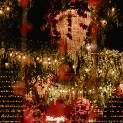 A view of the sangeet decor, showing how we layered elements to create depth. Cascading greenery, crystal chandeliers wrapped in red roses, and a backdrop of countless candles worked together to create a multi-dimensional, magical space.