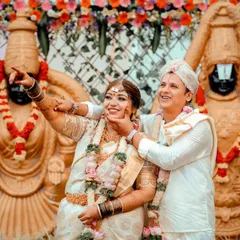 A fun and candid moment with the couple in front of deity statues at their wedding. Their joyful expressions show the happiness of the day.