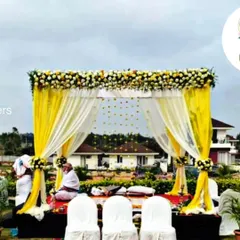For outdoor ceremonies, I design beautiful mandaps that complement the natural surroundings. This setup uses bright yellow drapes and white floral arrangements to create a cheerful and elegant space for a daytime wedding.