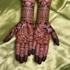 This design showcases a very dark and rich henna stain. The pattern is dense with floral work and paisleys, covering the entire hand for a dramatic effect.