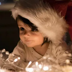 Another angle from our Christmas-themed newborn session. This shot captures a gentle, thoughtful expression as the baby looks away from the camera, showcasing the beautiful soft lighting and cozy atmosphere.