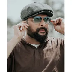 A casual outdoor portrait with a cool, relaxed vibe. The sunglasses and cap add a touch of style, making it a great shot for a personal profile or lifestyle feature.