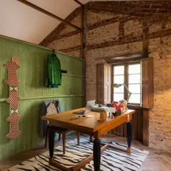 My personal cabin in the studio. I kept the exposed brick and stone walls and paired them with a bold green accent wall and a zebra-print rug. It’s a space that feels creative and inspiring, blending raw, historical textures with eclectic, modern touches.