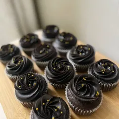 A batch of our elegant chocolate cupcakes, topped with rich chocolate frosting and delicate gold sprinkles. These were packed as return favors for a little one's birthday.