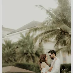 A classic, romantic portrait with a beautiful destination feel. The couple shares a loving gaze against a backdrop of palm trees and elegant architecture, telling a story of calm, powerful love.