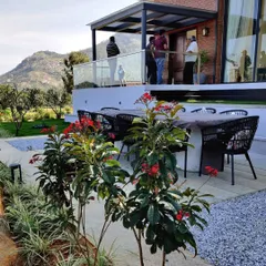 An outdoor dining area set on a gravel and stone patio overlooking the Nandi Hills. This space was designed for entertaining, providing a durable and elegant surface that connects the home's interior with the expansive garden and scenic views.