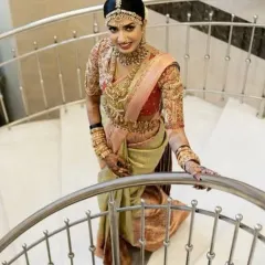 A full-length view of a stunning South Indian bride, showcasing the complete look from the elaborate hair jewellery down to the perfectly draped saree.