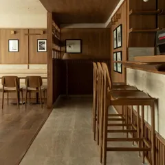 The main seating area and bar, defined by a consistent language of wood paneling and minimalist furniture. The space is designed to be a calm, uncluttered retreat from the city.