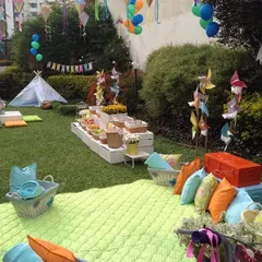 A cozy picnic setup on a lush green lawn. I used colorful cushions, blankets, and a teepee to create a relaxed and playful atmosphere for a birthday celebration.