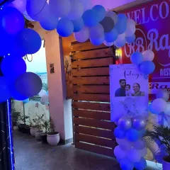 The entrance to the elephant-themed birthday party, decorated with a simple blue and white balloon arch and a welcome standee featuring a family photo.