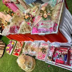 An elaborate display of wedding gifts ready for presentation. This collection includes heavily embellished trays for sarees or lehengas, smaller boxes for cosmetics and sweets, and a decorative birdcage element.