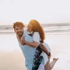 A fun piggyback ride on the beach at sunset. This candid shot is full of laughter and genuine affection, perfectly capturing the couple's playful dynamic.