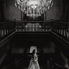 A dramatic, wide-angle black and white shot of the bride on the grand staircase. This image emphasizes the scale of the venue and the elegance of the moment.